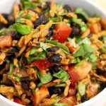 Black bean salad with shredded carrots in a white bowl