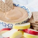 Pumpkin yogurt dip in blue and white bowl with graham crackers and apples