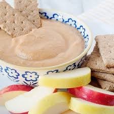 Pumpkin yogurt dip in blue and white bowl with graham crackers and apples