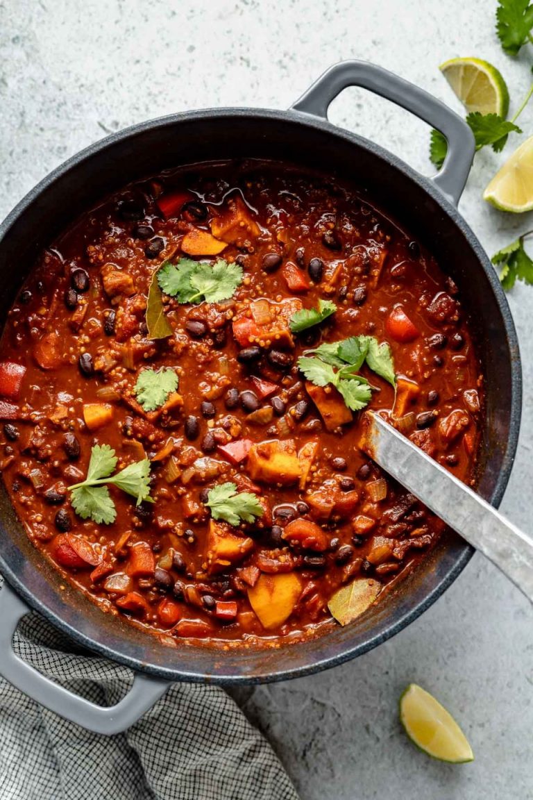 Sweet potato, black bean, quinoa chili in a pot with serving spoon on table