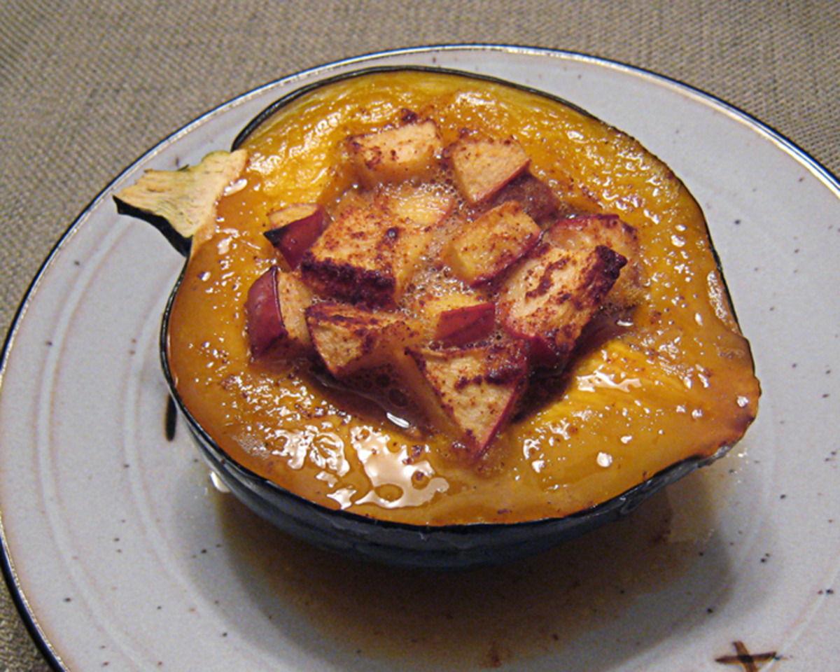 Baked acorn squash with apples on a white plate on a table.
