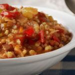 Barley jambalaya in a white bowl on a blue and white tablecloth
