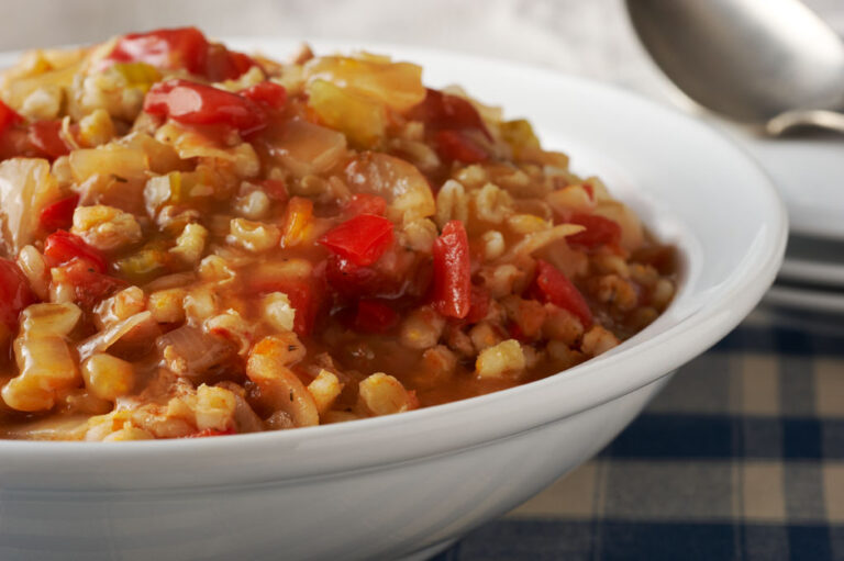 Barley jambalaya in a white bowl on a blue and white tablecloth