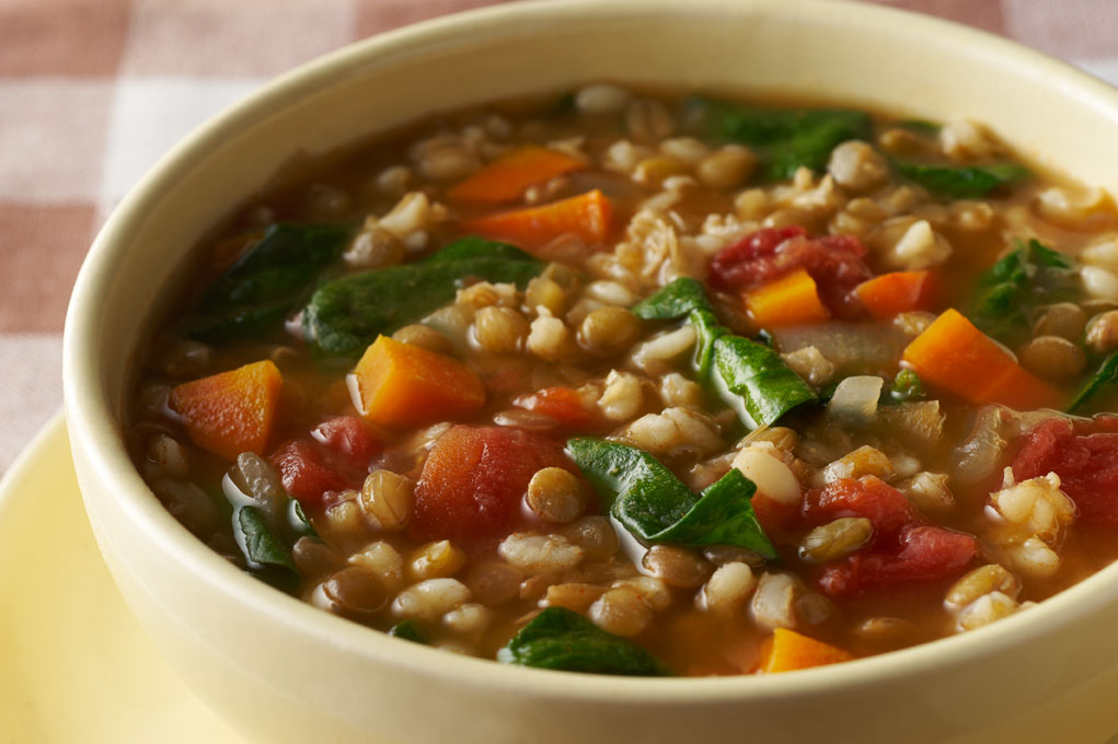 Barley and lentil soup in a white bowl on a red and white tablecloth