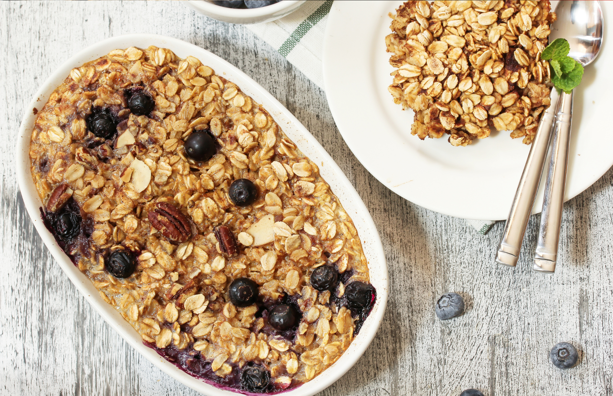Blueberry baked oatmeal in an oval white dish pictured on a wooden table
