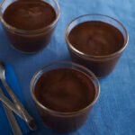 Chocolate pudding in glass cups on table with flatware