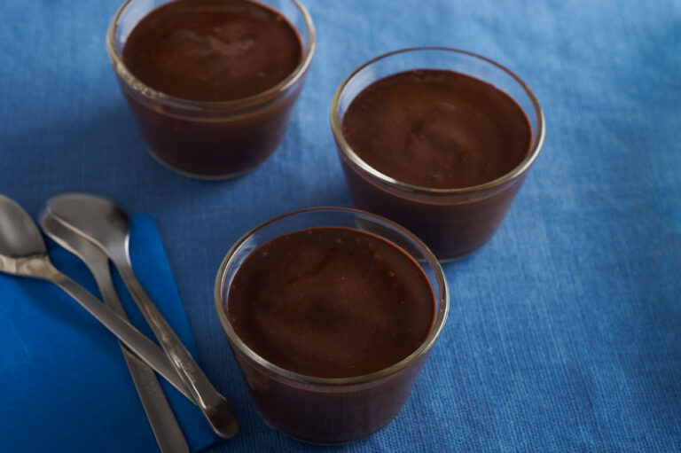 Chocolate pudding in glass cups on table with flatware