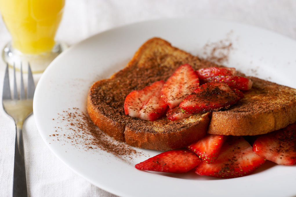 Chocolate strawberry French toast on a white plate with strawberries.