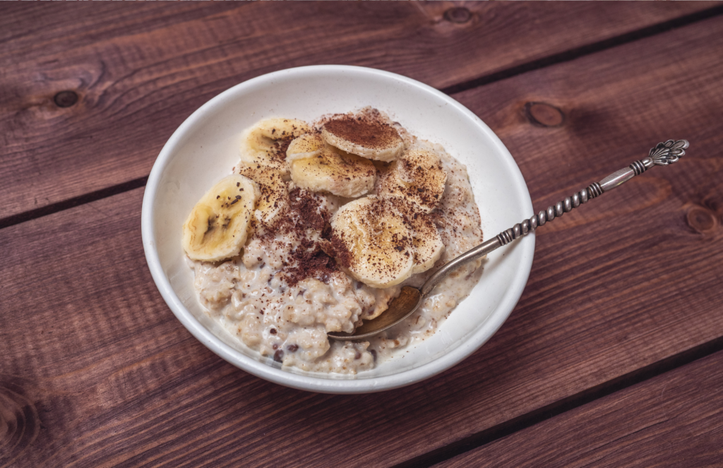 Banana chocolate chip overnight oats in a white bowl with spoon on a wooden table.