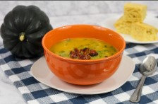Acorn squash soup in orange bowl with blue check table cloth