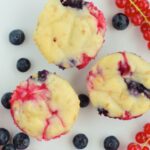 Berry muffins with blueberries and grapes on a white plate.