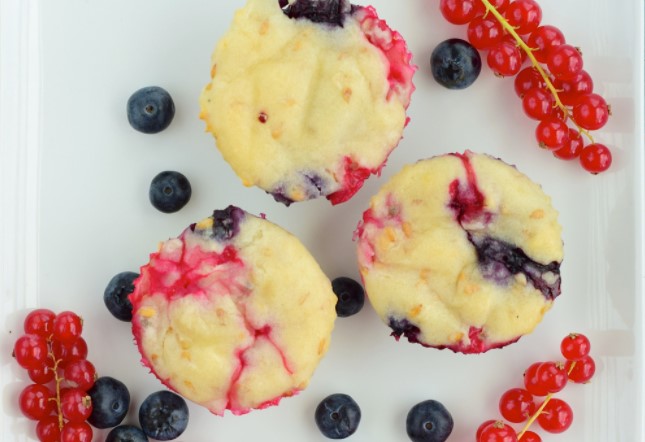 Berry muffins with blueberries and grapes on a white plate.