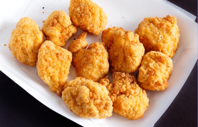 Chicken nuggets on a white serving dish.