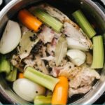 Chicken stock in pot with celery, onions, carrots