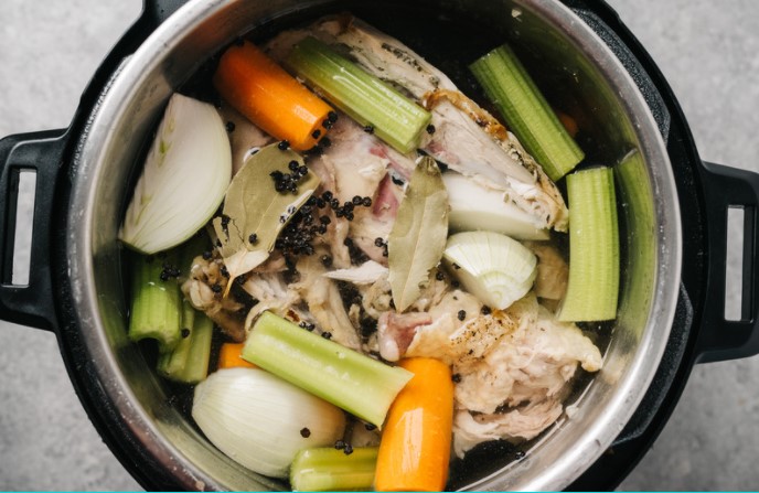 Chicken stock in pot with celery, onions, carrots