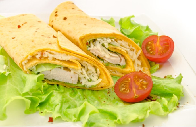 Chicken wraps with corn tortillas, on a bed of lettuce with fresh tomatoes.