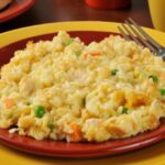 Chicken and Rice Casserole on a red plate with a fork on a yellow serving plate.