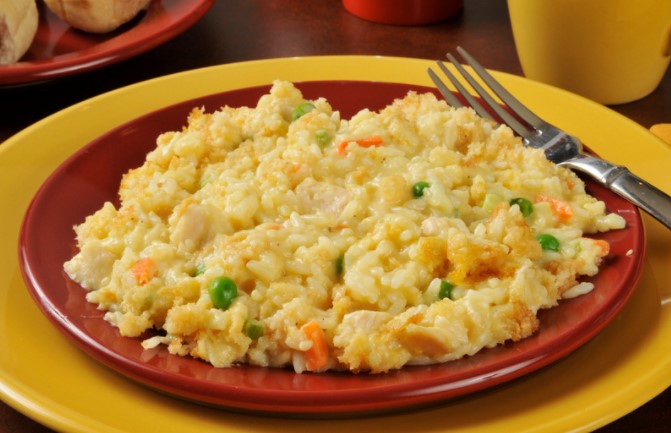 Chicken and Rice Casserole on a red plate with a fork on a yellow serving plate.