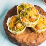 Chicken and Vegetable Muffins on a wooden serving board on a light blue table.