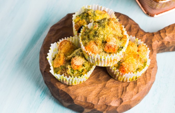 Chicken and Vegetable Muffins on a wooden serving board on a light blue table.