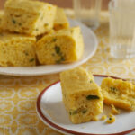 Confetti cornbread of a white plate pictured on a yellow and white tablecloth
