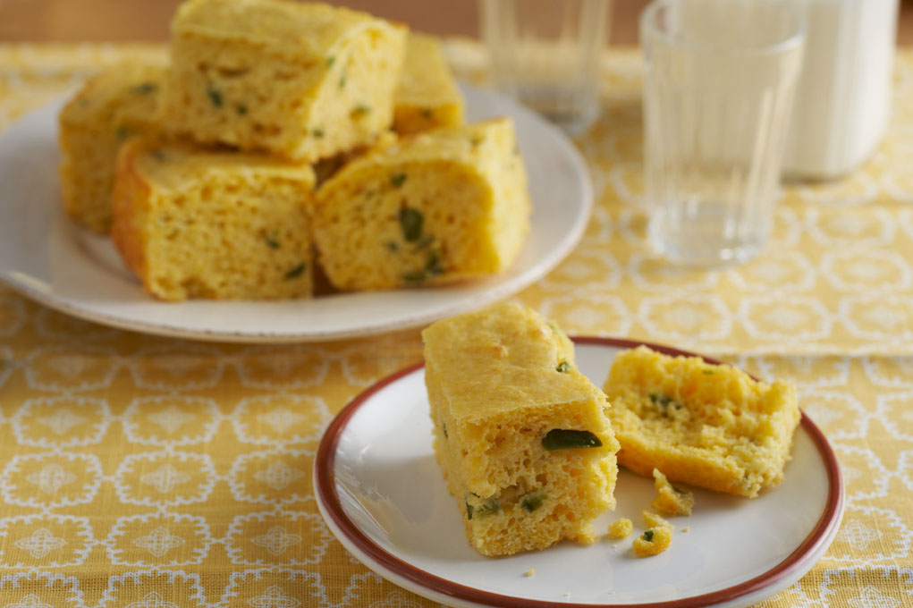 Confetti cornbread of a white plate pictured on a yellow and white tablecloth