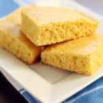 Dairy free cornbread on a white square plate on top of a blue and white tablecloth.