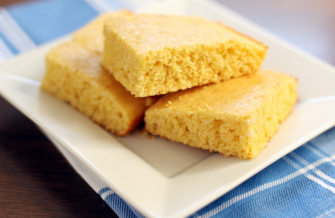 Dairy free cornbread on a white square plate on top of a blue and white tablecloth.