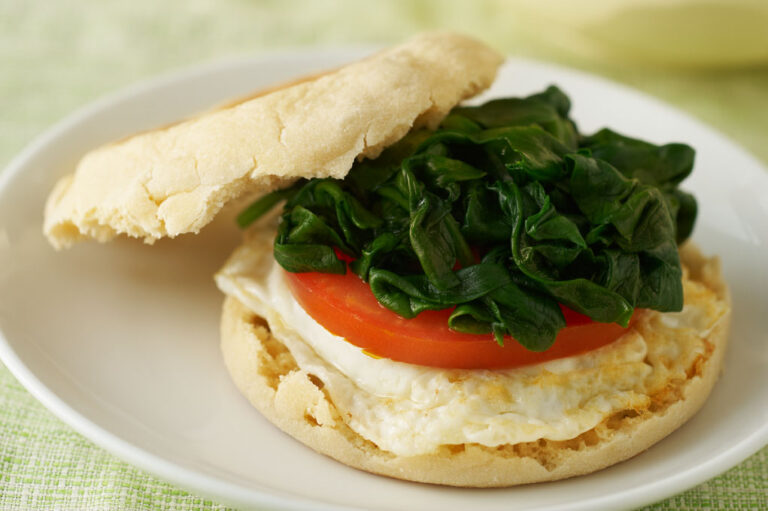 English muffin breakfast sandwich on a white plate.