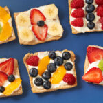 Fruit tarts placed on a solid blue tablecloth.