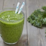 Green smoothie with kale on a wooden table.