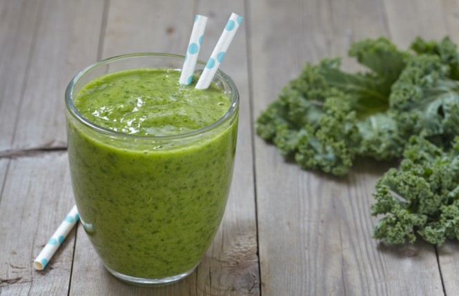 Green smoothie with kale on a wooden table.
