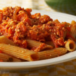 Hearty vegetable pasta on a white plate.