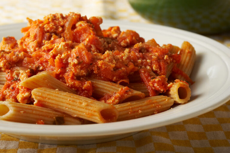 Hearty vegetable pasta on a white plate.