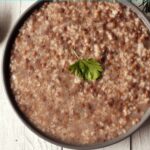 Lentil and rice soup with a spoon on a wooden table.