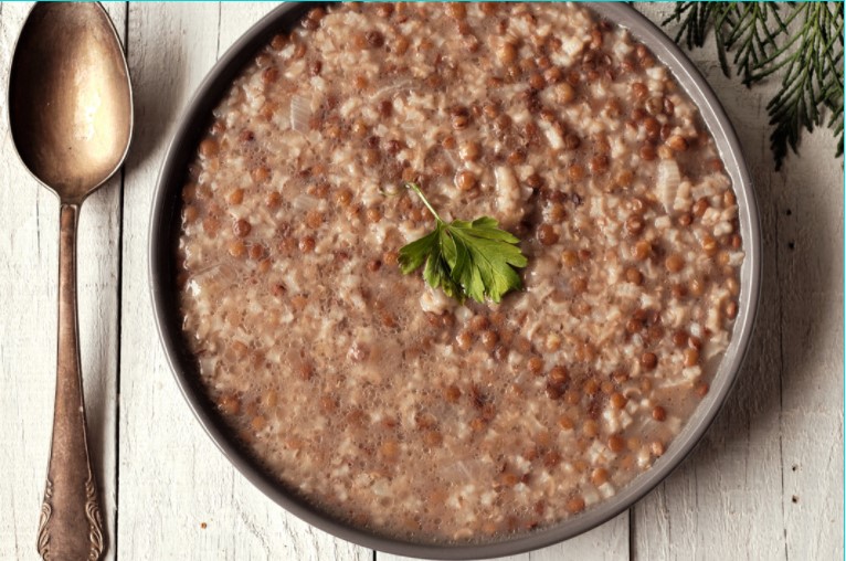 Lentil and rice soup with a spoon on a wooden table.