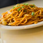 Lo mein on a white dish on top of a white table.