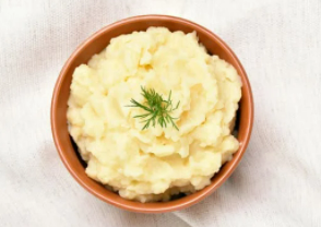 Mashed potatoes in an rusty orange bowl on with a white background.
