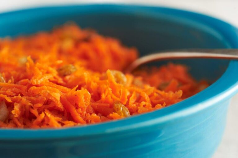 Shredded carrots with spices in a blue bowl.