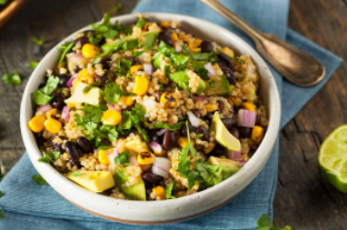 One pot Mexican quinoa in white bowl on blue napkin on wooden table.