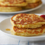 Two orange oatmeal pancakes on a white plate with strawberries.