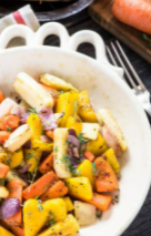 Colorful oven roasted root vegetables in a white serving dish.
