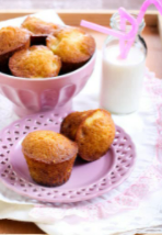 Two pineapple carrot muffins sitting on lilac colored dish with lilac colored bowl on table.