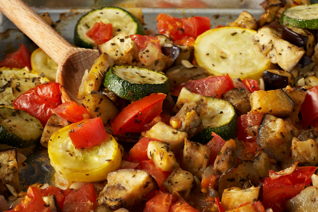 One serving dish of ratatouille with a wooden spoon.