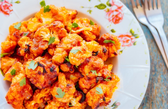 Roasted buffalo cauliflower on a white plate with flowers.