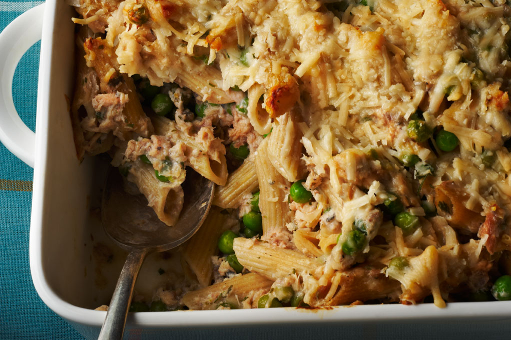 Casserole dish with salmon pasta bake and a metal serving spoon.