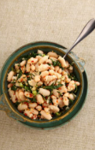 Dark bowl with soldier bean salad and a metal spoon.