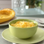 Pale green bowl with spaghetti squash on top of a pale green plate.