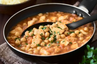 Black bowl with chicken soup and chickpeas.