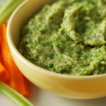Spicy white bean dip in a yellow bowl with bright orange carrots and lime green celery